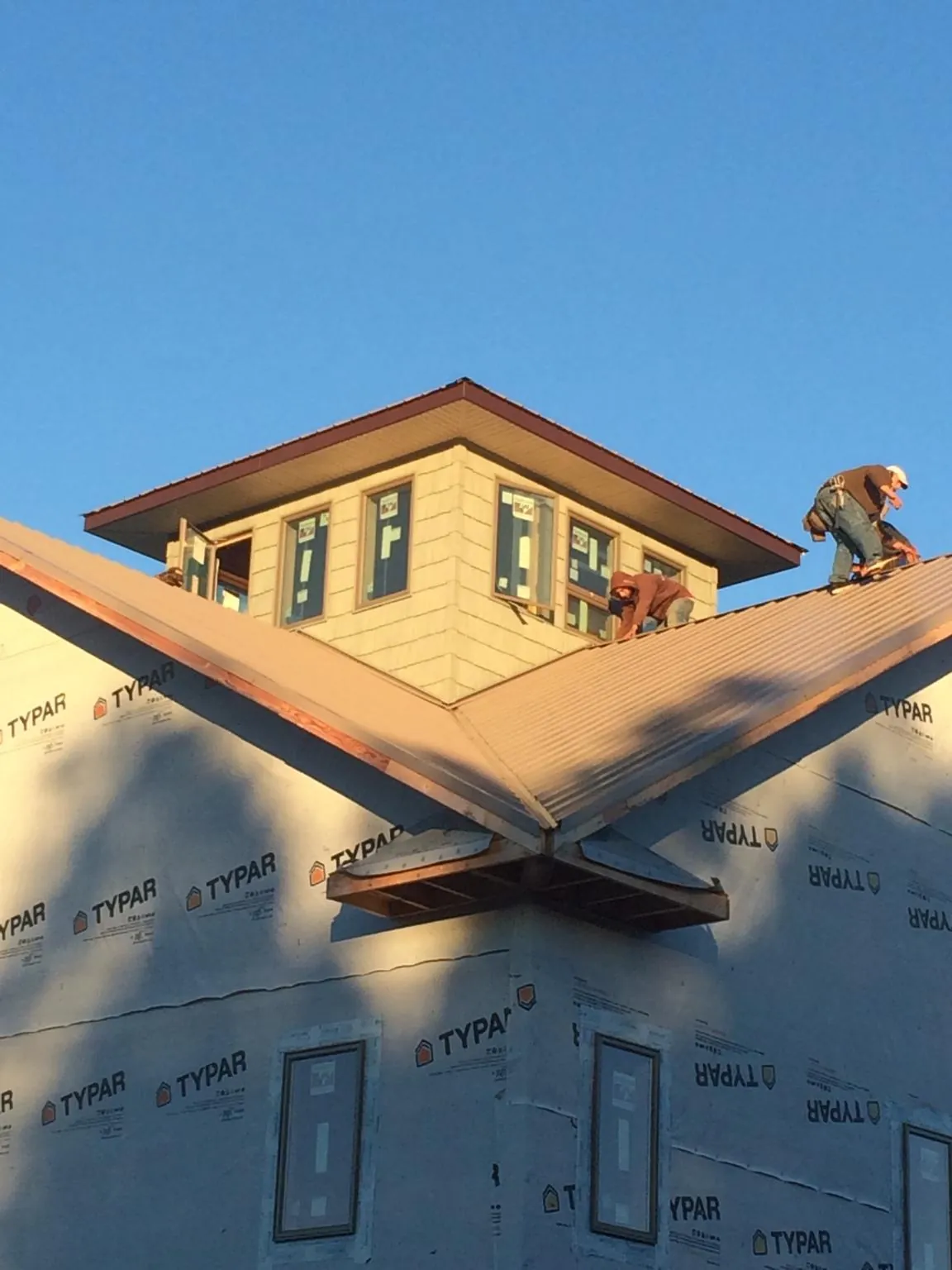 Roofers working around a rooftop cupola on a new metal roof at sunset — Roof Waterproofing in Hickman by Roofing Brothers